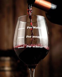 a wine glass filled with red wine being poured into it and labeled on the side