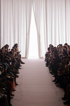 a large group of people sitting in front of a white curtained entrance to a room