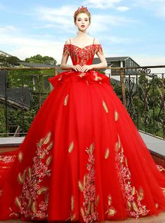 a woman in a red ball gown standing on a balcony with her hands on her hips