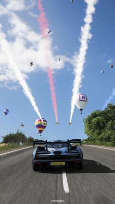 a car driving down a road with several balloons flying in the air