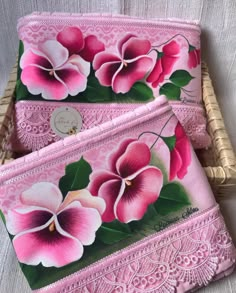 two pink flowered purses sitting on top of a white table next to a wicker basket