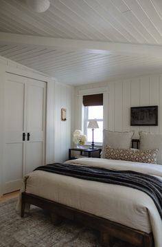 a bed sitting in a bedroom next to a white door and window on top of a rug