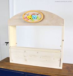 a wooden toy shelf with a clock on it's top and two drawers below