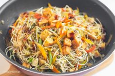 a wok filled with stir fry vegetables on top of a wooden spatula