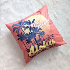 an orange pillow with the words aloh on it and palm trees in the background