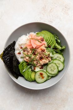 a bowl filled with rice, cucumbers and salmon