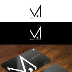 a black and white business card sitting on top of a wooden table with the letter m