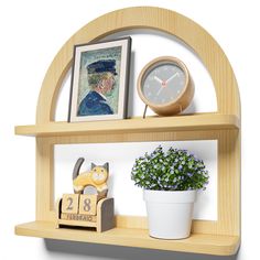 a wooden shelf with a clock, potted plant and pictures on it