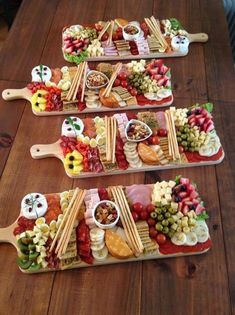 three serving trays filled with food on top of a wooden table next to each other