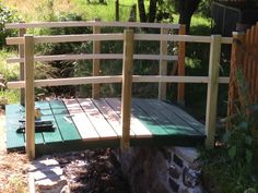 a wooden bridge over a small stream in a garden