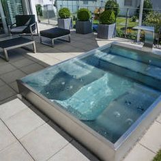 an outdoor hot tub on a patio with lounge chairs