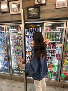 a woman standing in front of a refrigerator filled with drinks