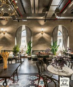 the interior of a restaurant with tables, chairs and chandeliers hanging from the ceiling