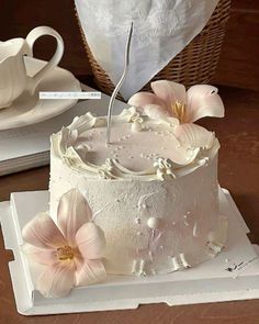 a white cake with pink flowers on it and a tea cup next to it,