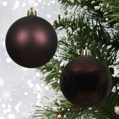 two ornaments hanging from a christmas tree with snow flakes on the branches behind them