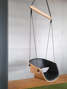 a swing chair hanging from the ceiling in a room with white walls and green grass