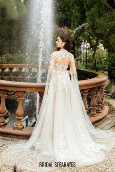 a woman standing in front of a fountain wearing a wedding dress with an open back