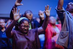 a group of people with their hands up in the air and one woman is wearing glasses