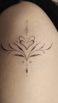 the back of a woman's thigh with a tattoo design on it, and an arrow in the shape of a heart