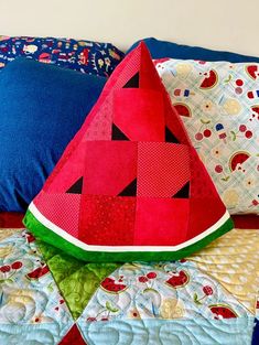 a watermelon pillow sitting on top of a bed next to a blue pillow