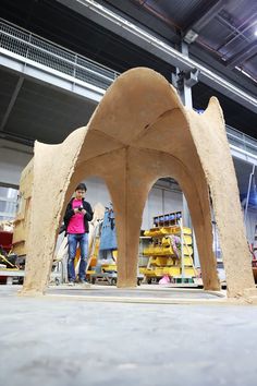 a woman is standing in front of a sculpture made out of clay and sand,