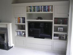 a living room filled with furniture and a flat screen tv on top of a book shelf