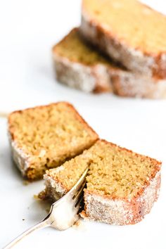 two pieces of cake on a white surface with a fork in the foreground and one slice missing