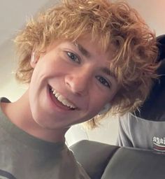 a man with curly hair is smiling at the camera