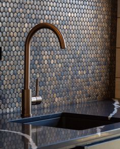 a kitchen sink sitting under a faucet next to a wall covered in circles