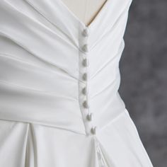 the back of a white wedding dress on a mannequin headdress with buttons