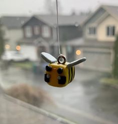 a yellow and black bee ornament hanging from a wire in front of a house