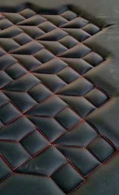 a close up of a black surface with red stitching on the top and bottom