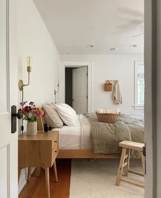 a bed sitting in a bedroom next to a wooden table with flowers on top of it