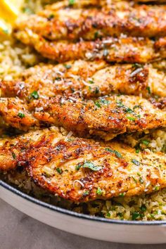 some food is in a pan with lemon wedges and parsley on the side