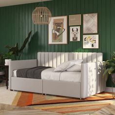 a bedroom with green walls and pictures on the wall, including a white bed frame