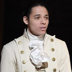 a woman wearing a white coat and gold buttons on her jacket is looking off to the side