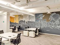 an office with white desks and chairs in front of a mural on the wall