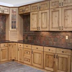 an empty kitchen with wooden cabinets and granite counter tops on the floor in front of a brick wall