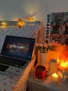 an open laptop computer sitting on top of a bed next to candles and other decorations