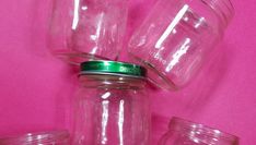 several empty glass jars are stacked on top of each other in front of a pink background