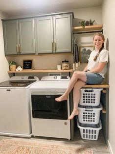 a woman sitting on top of a washer and dryer in a laundry room