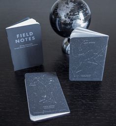 three books sitting on top of a table next to a silver ball and a glass globe