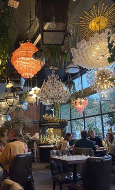 people sitting at tables in a restaurant with chandeliers hanging from the ceiling