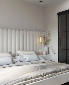 a white bed sitting next to a black door in a room with lots of pillows