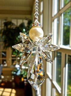 a crystal ornament with a pearl hanging from it's side in front of a window