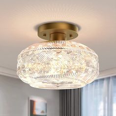 a ceiling light that is hanging from the ceiling in a room with curtains and windows