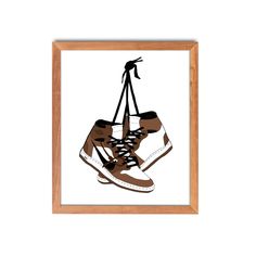 a pair of shoes hanging from a hook on a wall in a wooden framed frame