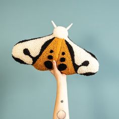 a hand holding up a knitted animal shaped like a bee