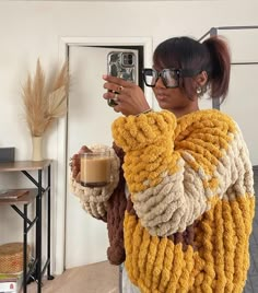 a woman taking a selfie with her cell phone while holding a cup of coffee