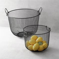 two wire baskets filled with fruit on top of a table